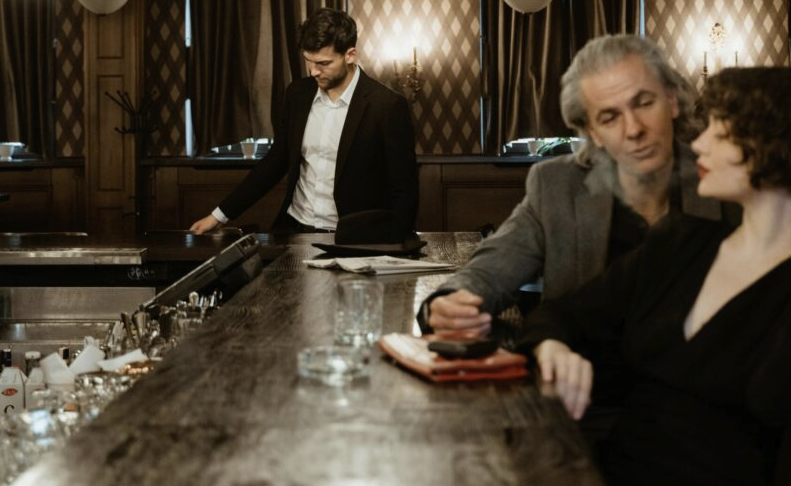 Sophisticated bar scene with people interacting at a stylish counter.